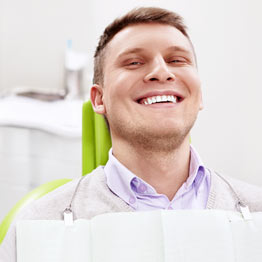A man smiling while sitting in a dentist's chair